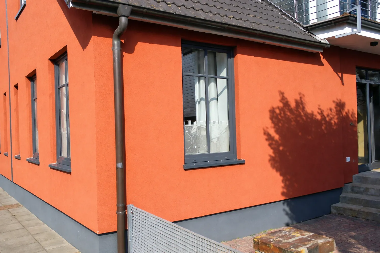 Seitenansicht des orangefarbenen Ferienhauses Roter Seestern mit Fenstern und Eingangsbereich