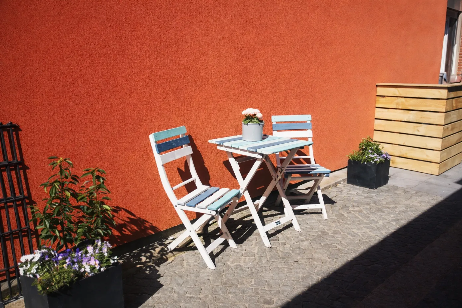 Gemütliche Sitzecke vor dem Ferienhaus Seepferdchen mit weißen Klappstühlen und Blumenkästen